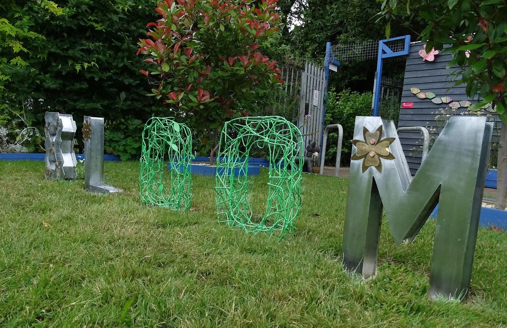 The word bloom is written in metal letters in the grass