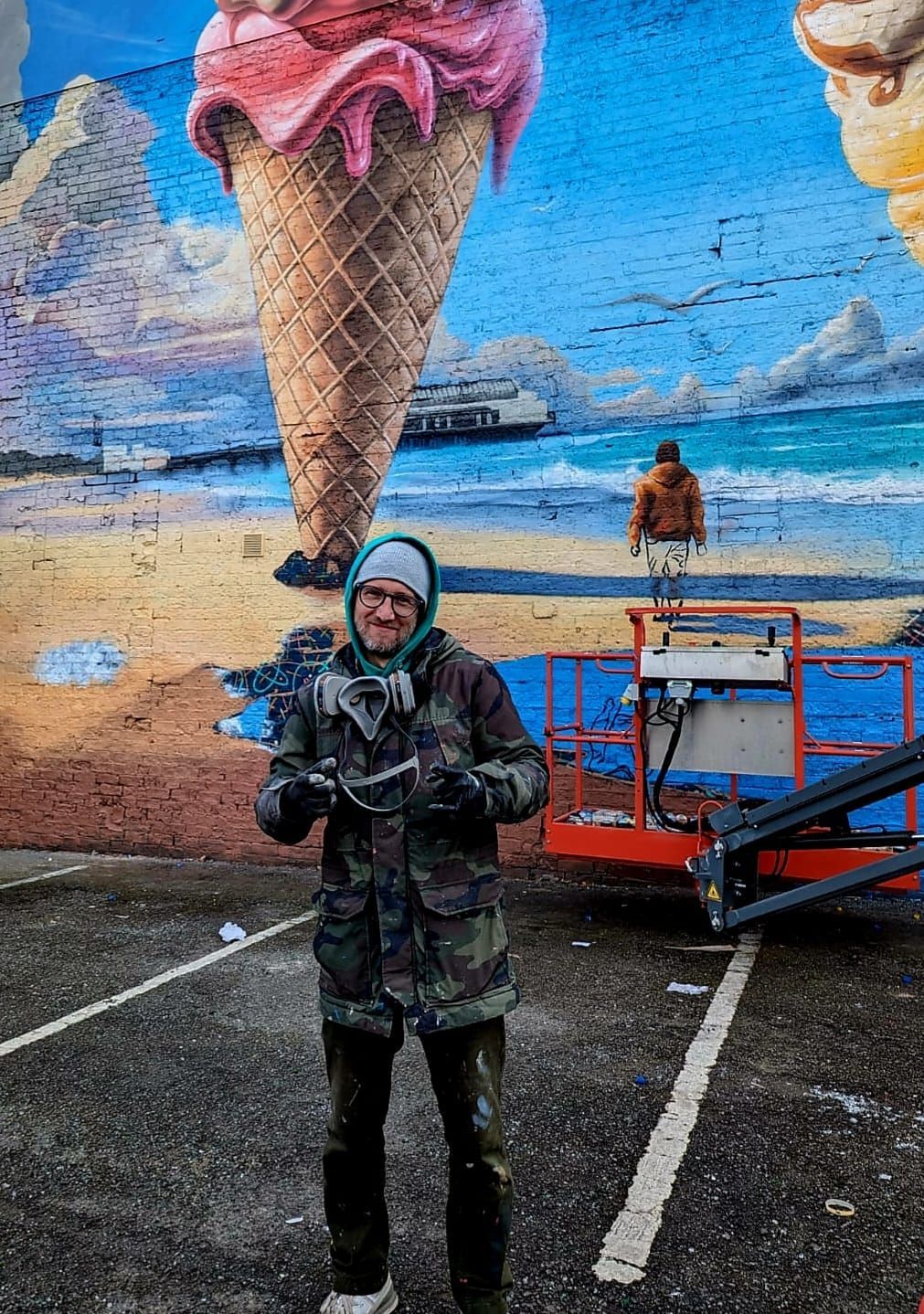 A man is standing in front of a mural of an ice cream cone.