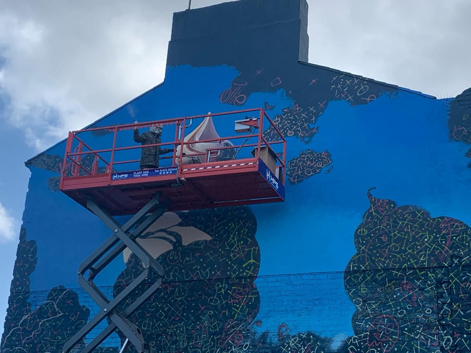 A man is painting a mural on the side of a building