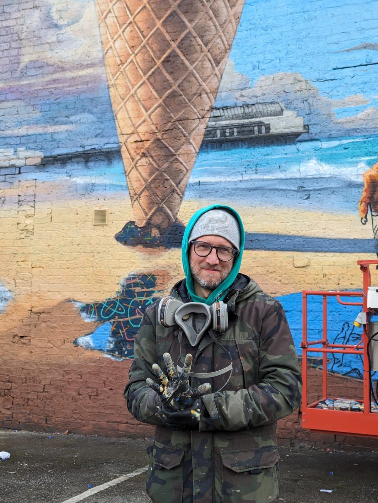 A man is standing in front of a mural of an ice cream cone.