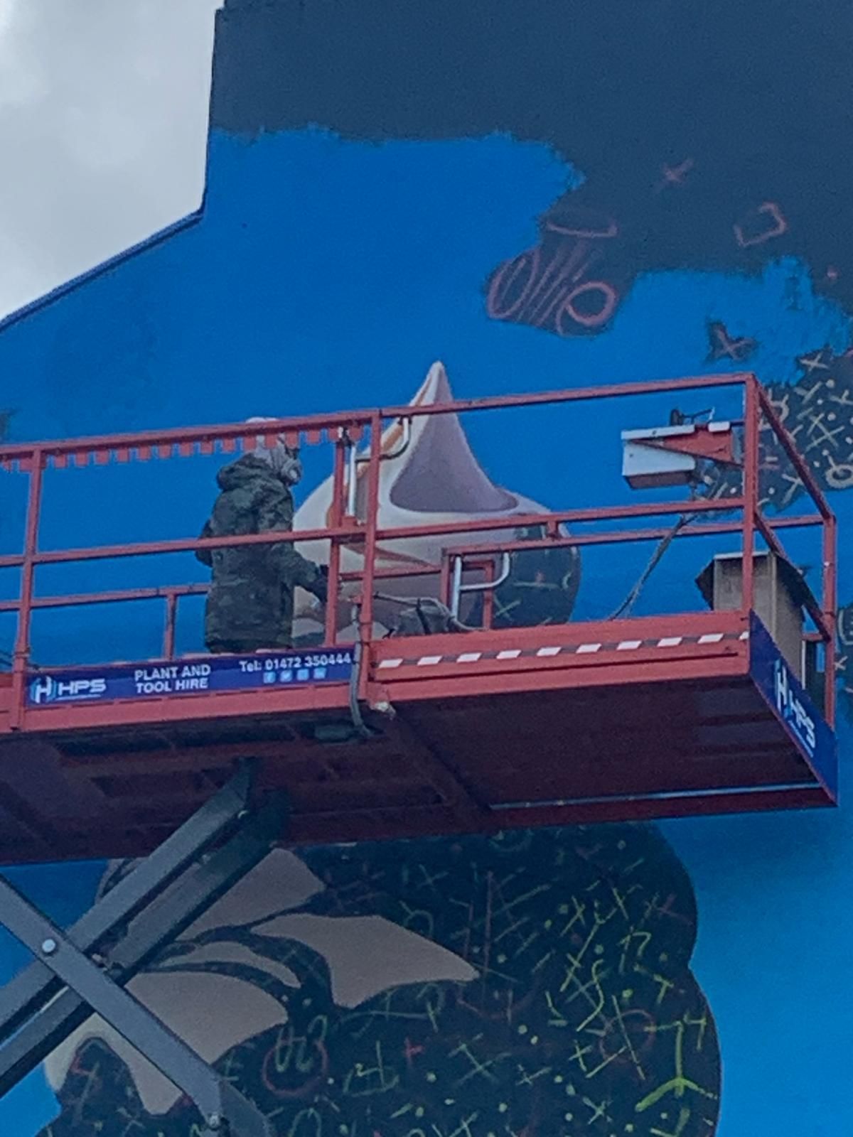 A man is painting a mural on the side of a building