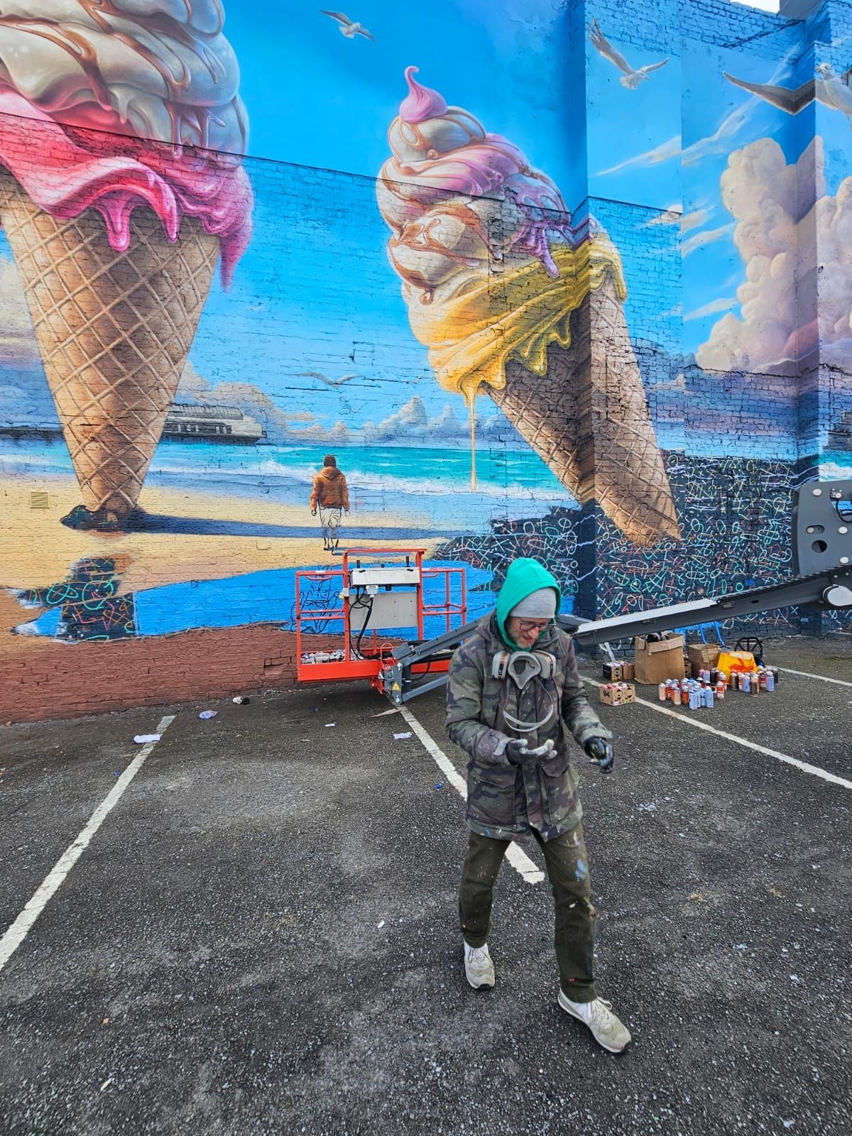 A man is standing in front of a large mural of ice cream cones.