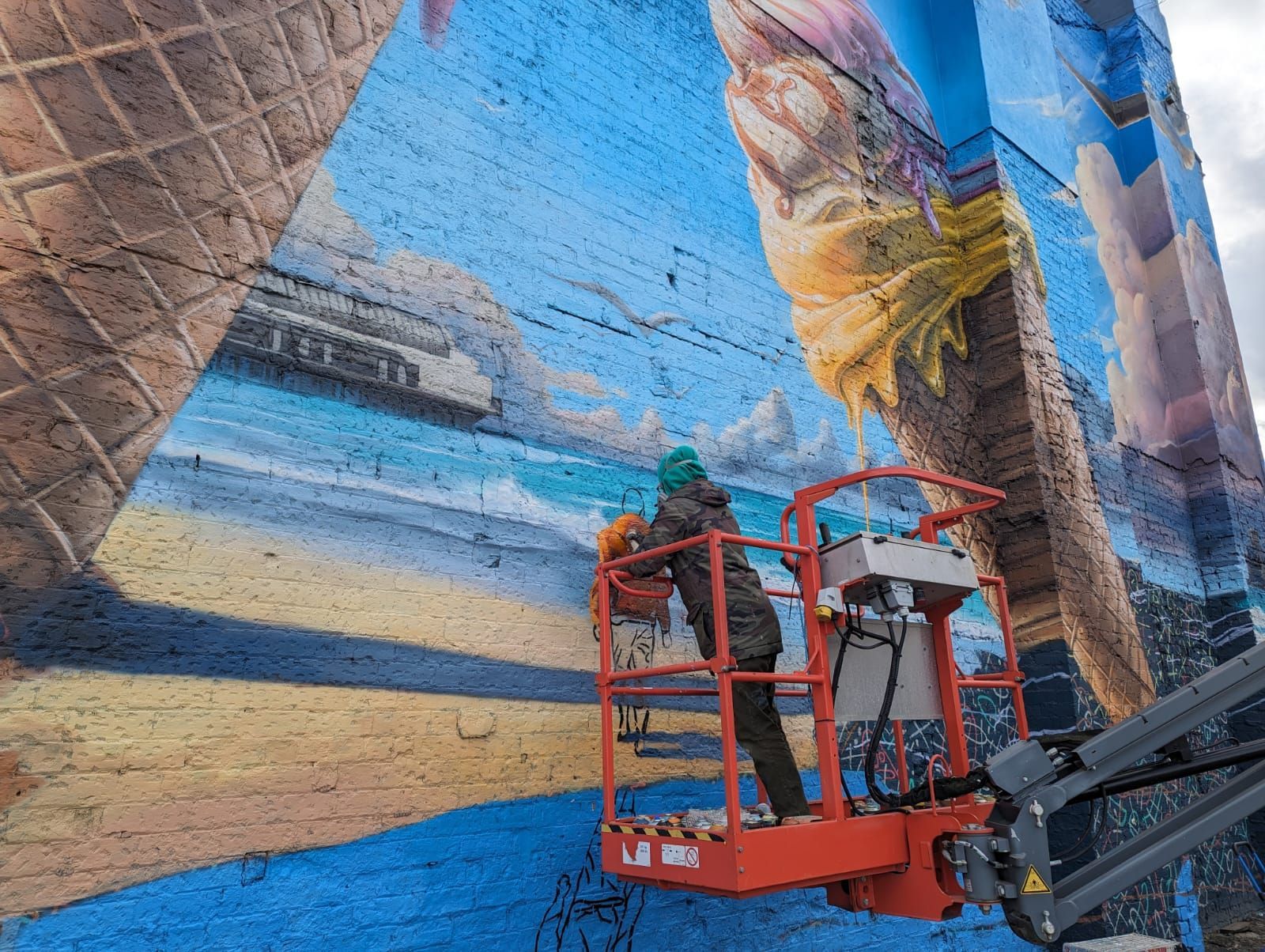 A man is painting a mural on the side of a building.