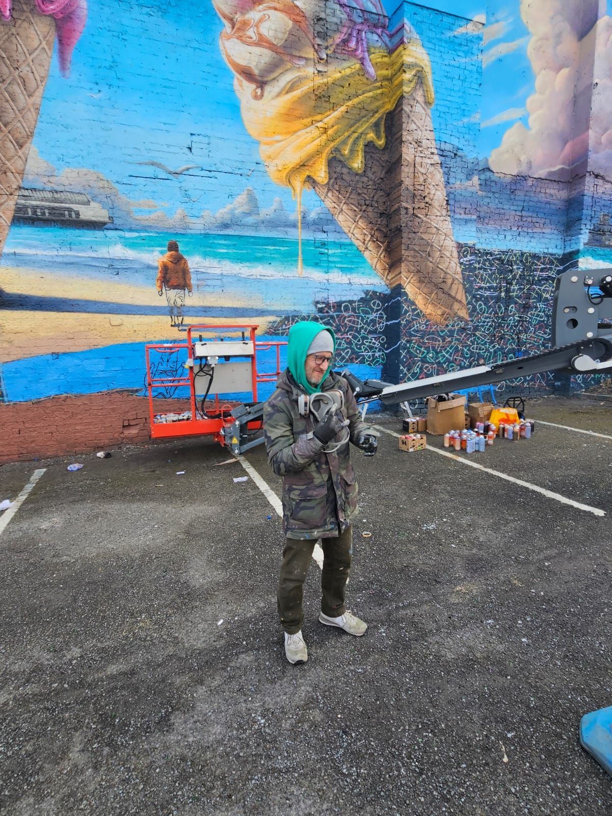 A man is standing in front of a large mural of ice cream cones.