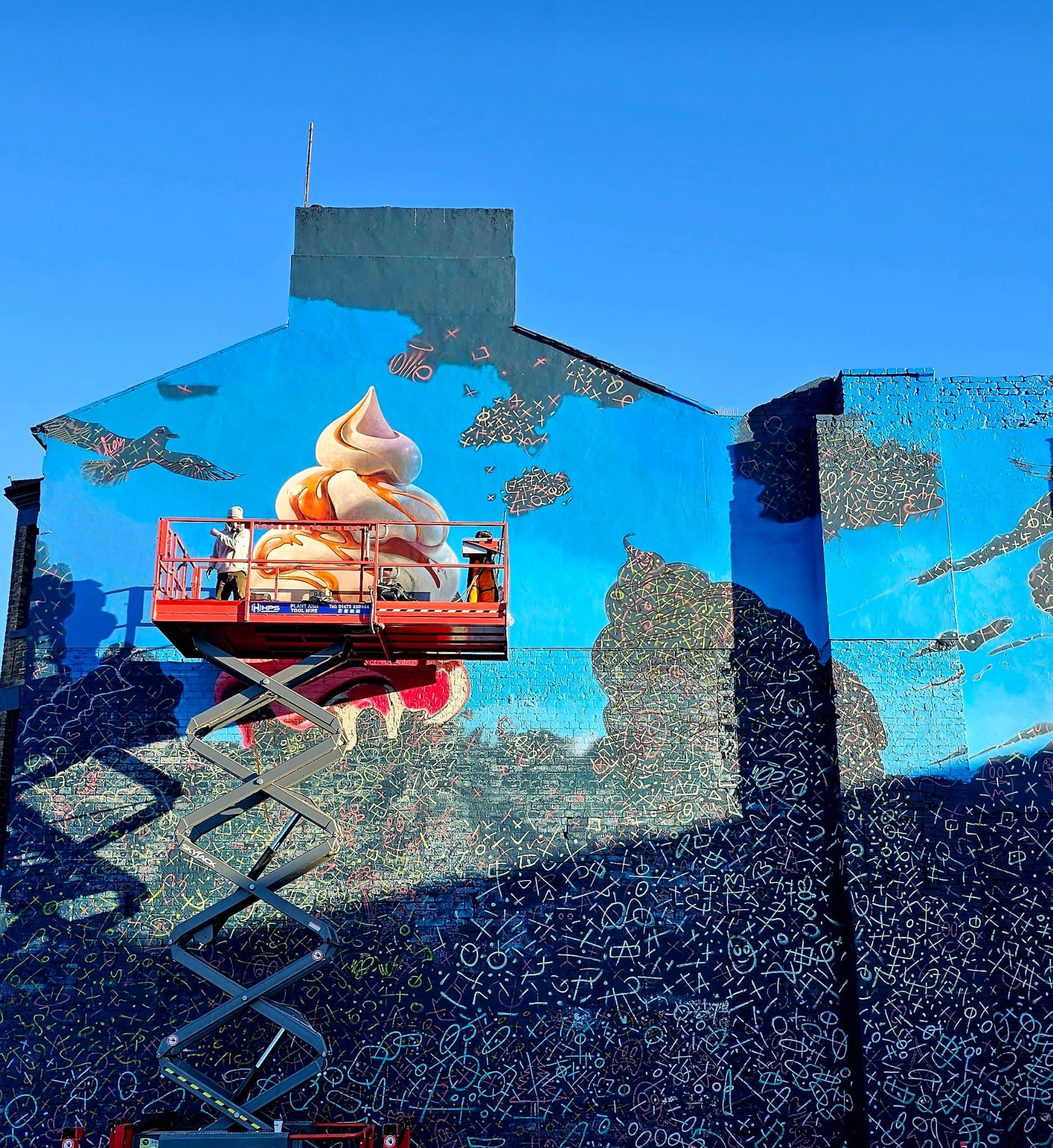 A painting of ice cream is being painted on the side of a building