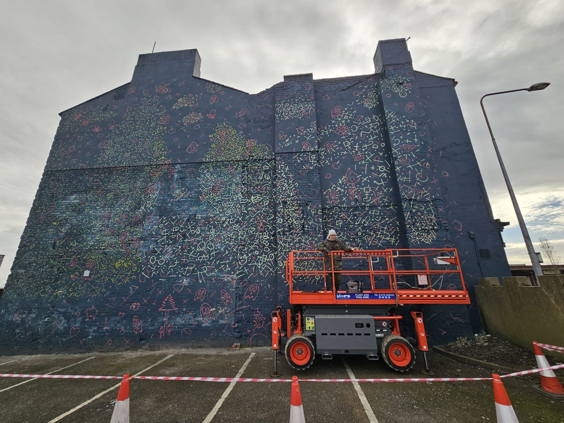 A crane is sitting in front of a large blue building.