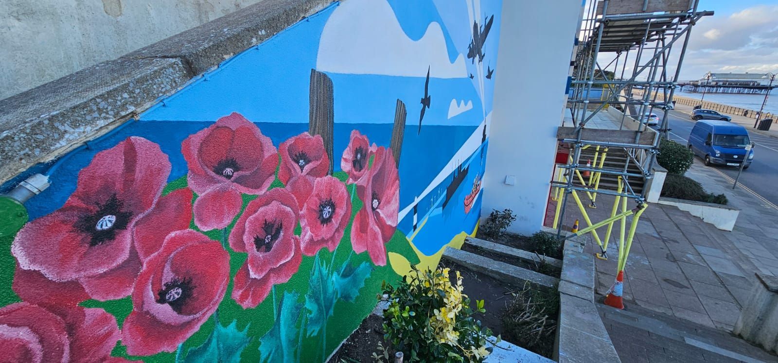A wall with a painting of red flowers on it