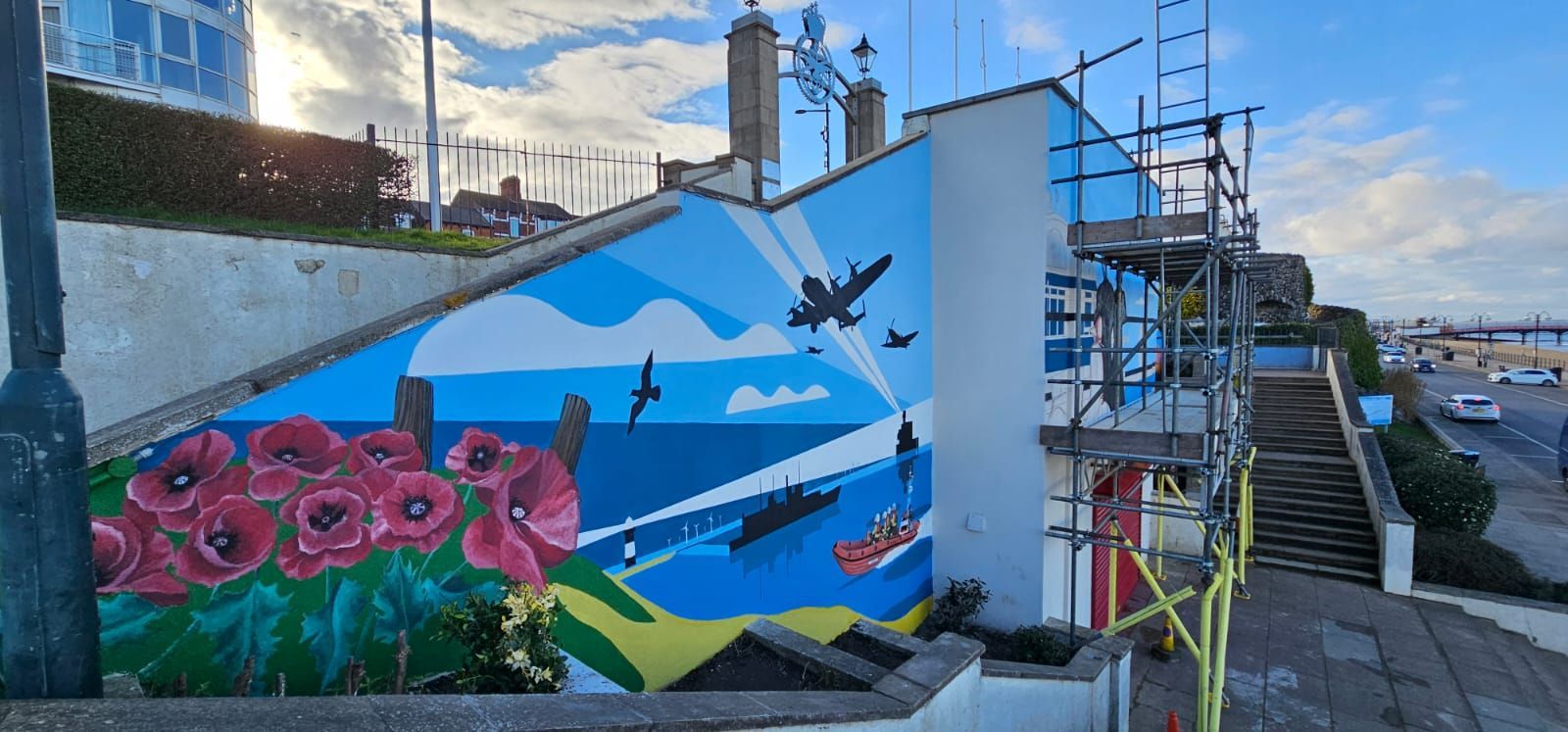 A mural on the side of a building is being painted.