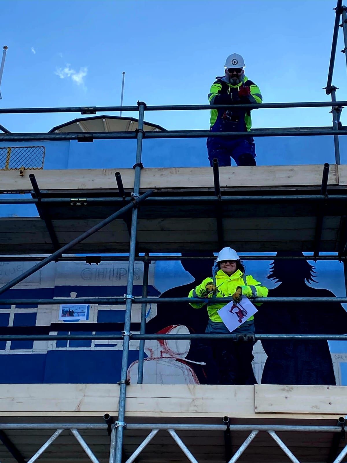 A man in a hard hat is standing on a scaffolding
