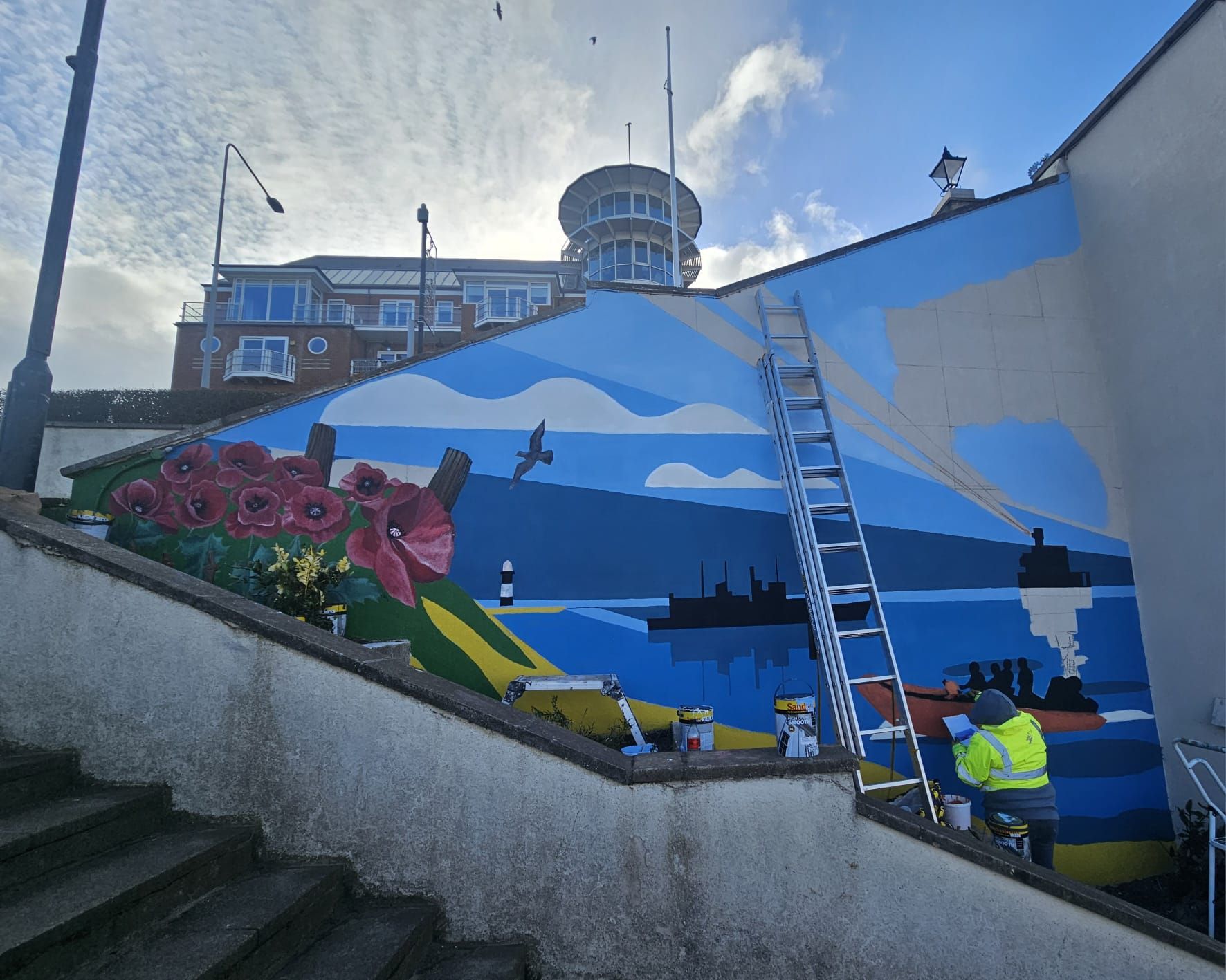 A man is painting a mural on the side of a building