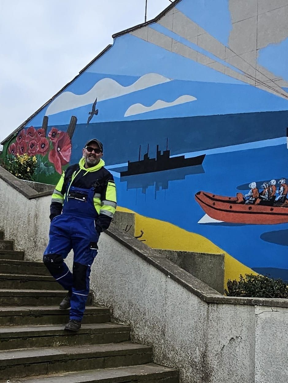 A man is standing on a set of stairs in front of a mural