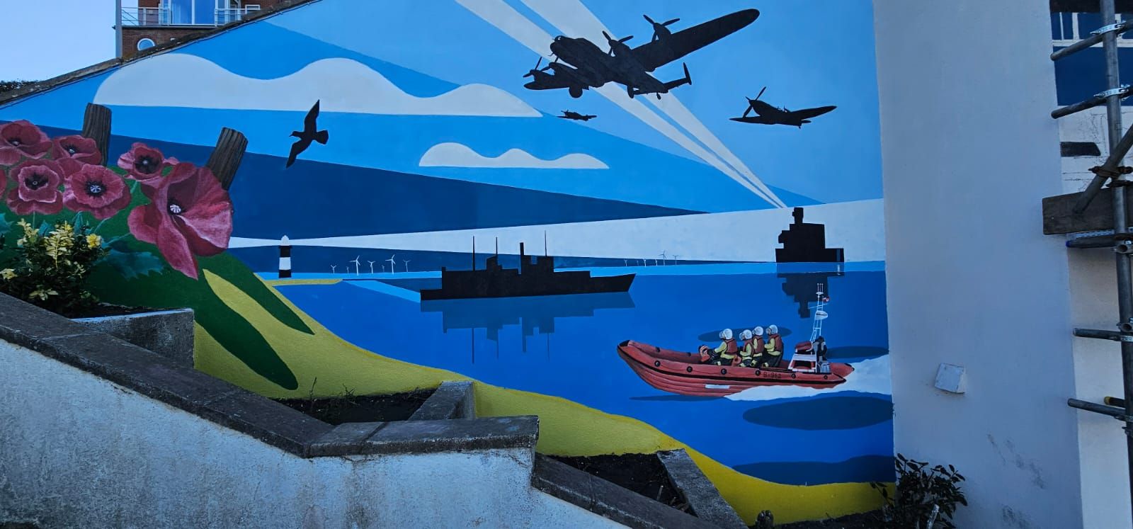 A mural on the side of a building shows planes flying over a body of water