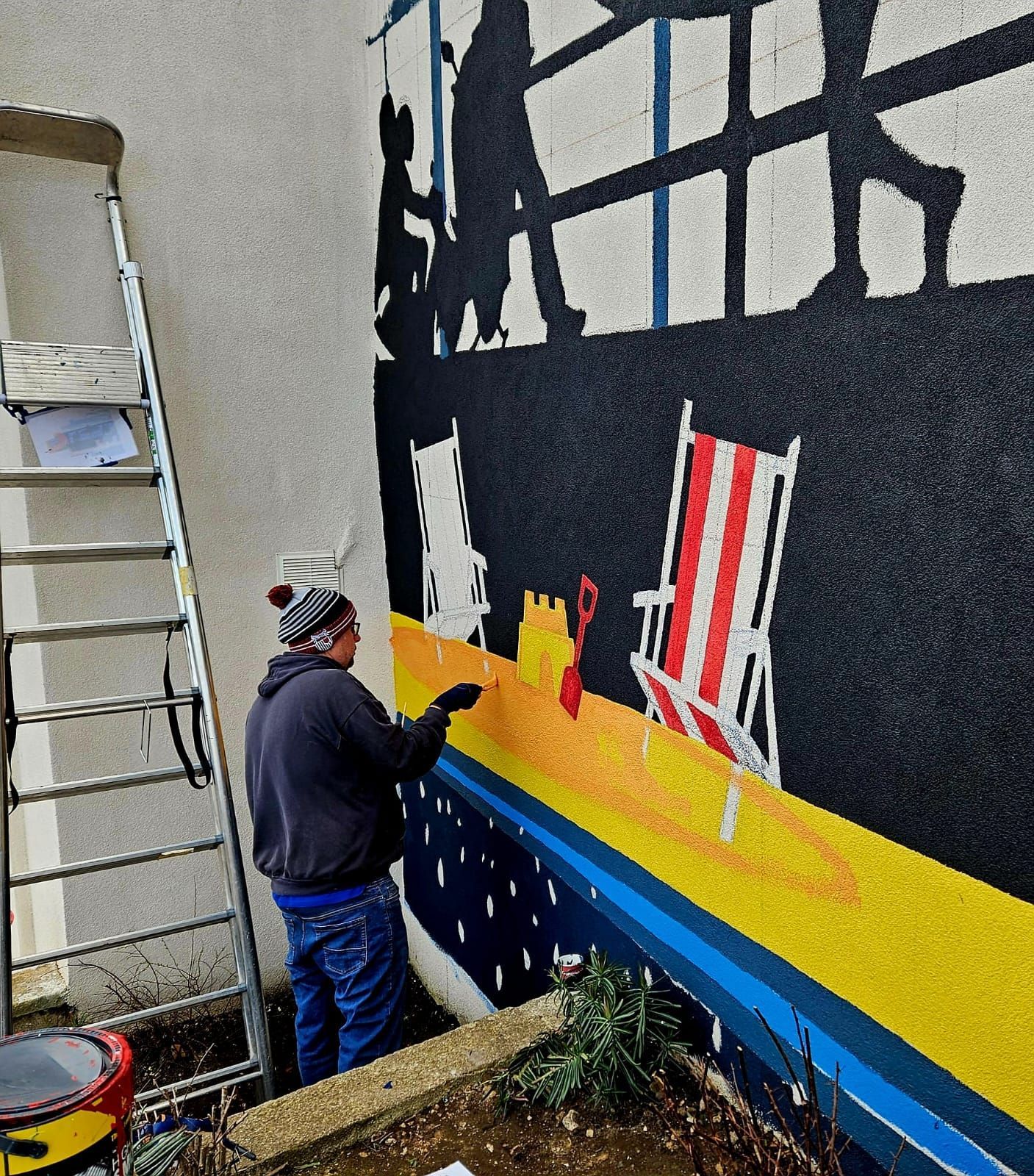 A man is painting a mural on the side of a building