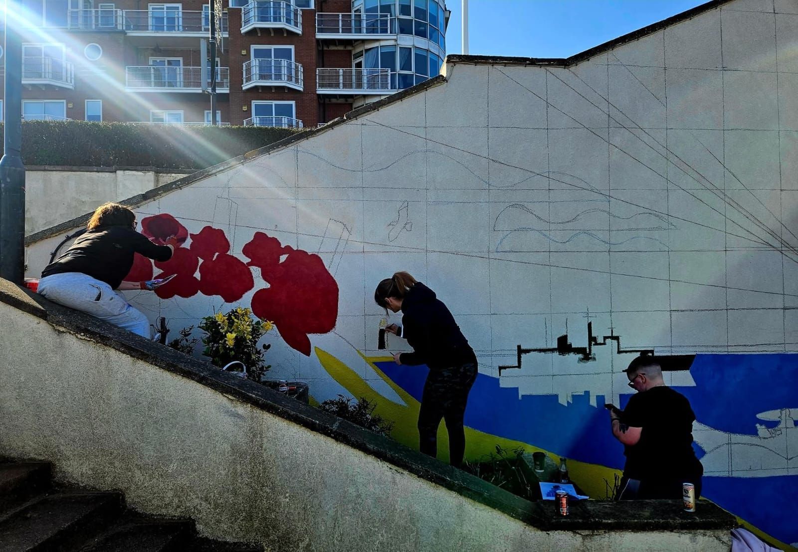 A group of people are painting a mural on a wall