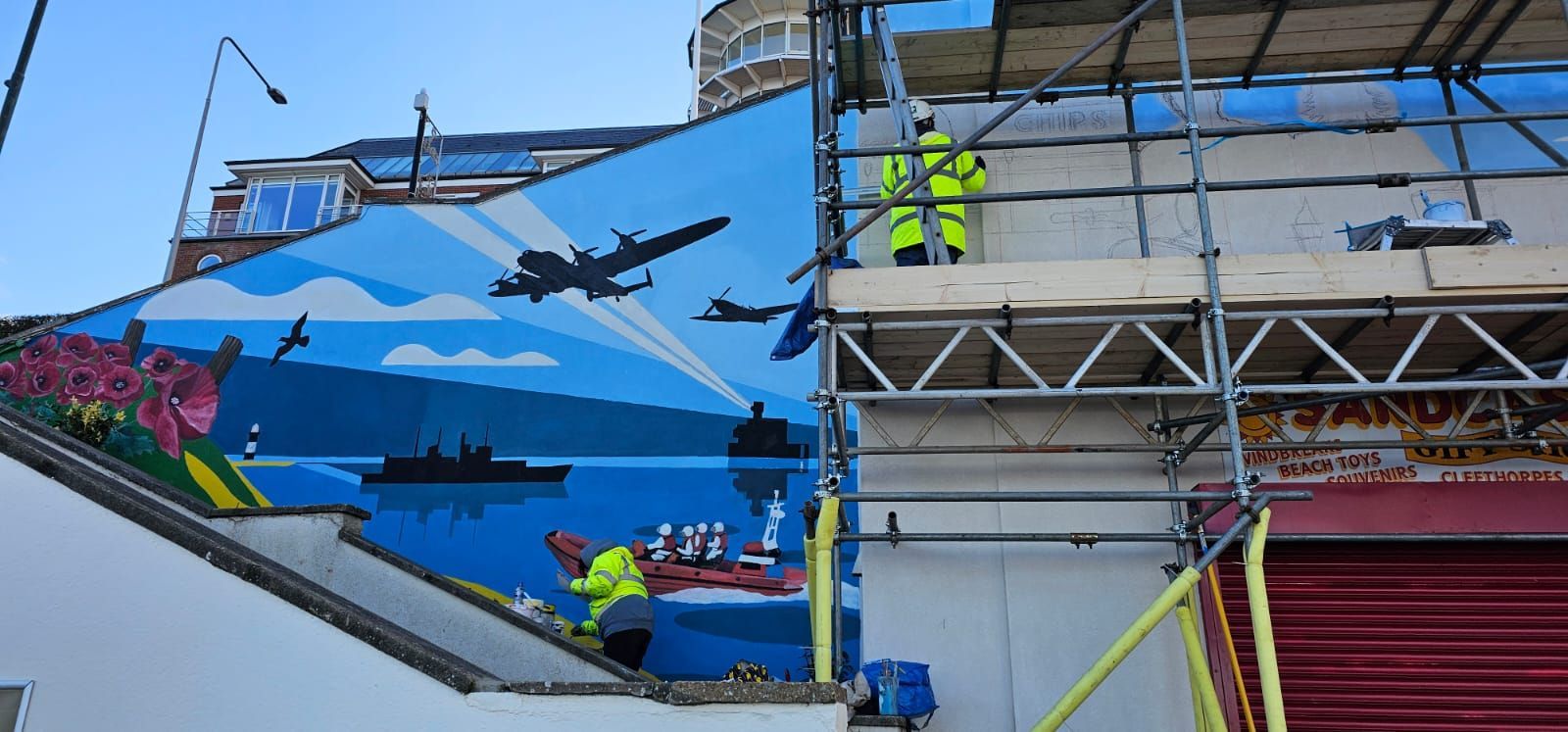 A large mural is being painted on the side of a building.