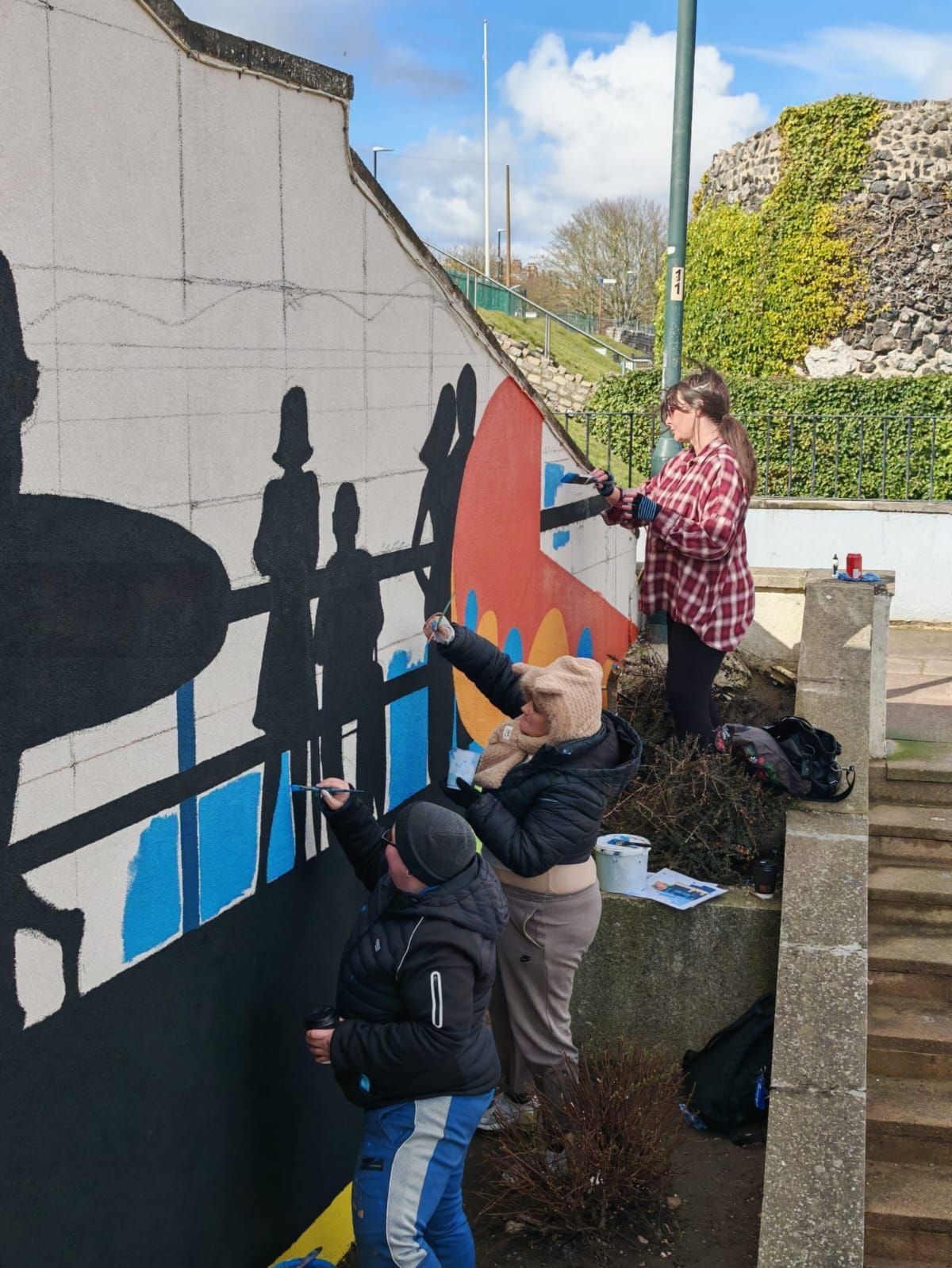 A group of people are painting a mural on a wall