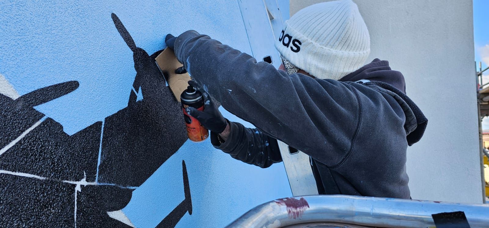 A man is painting a mural on the side of a building.