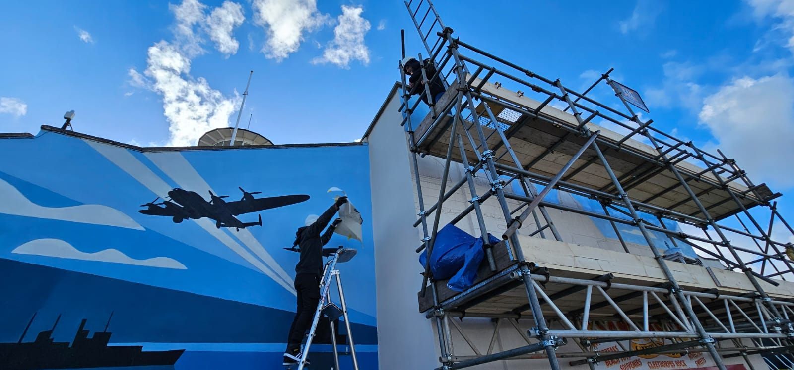 A man is painting a mural on the side of a building.