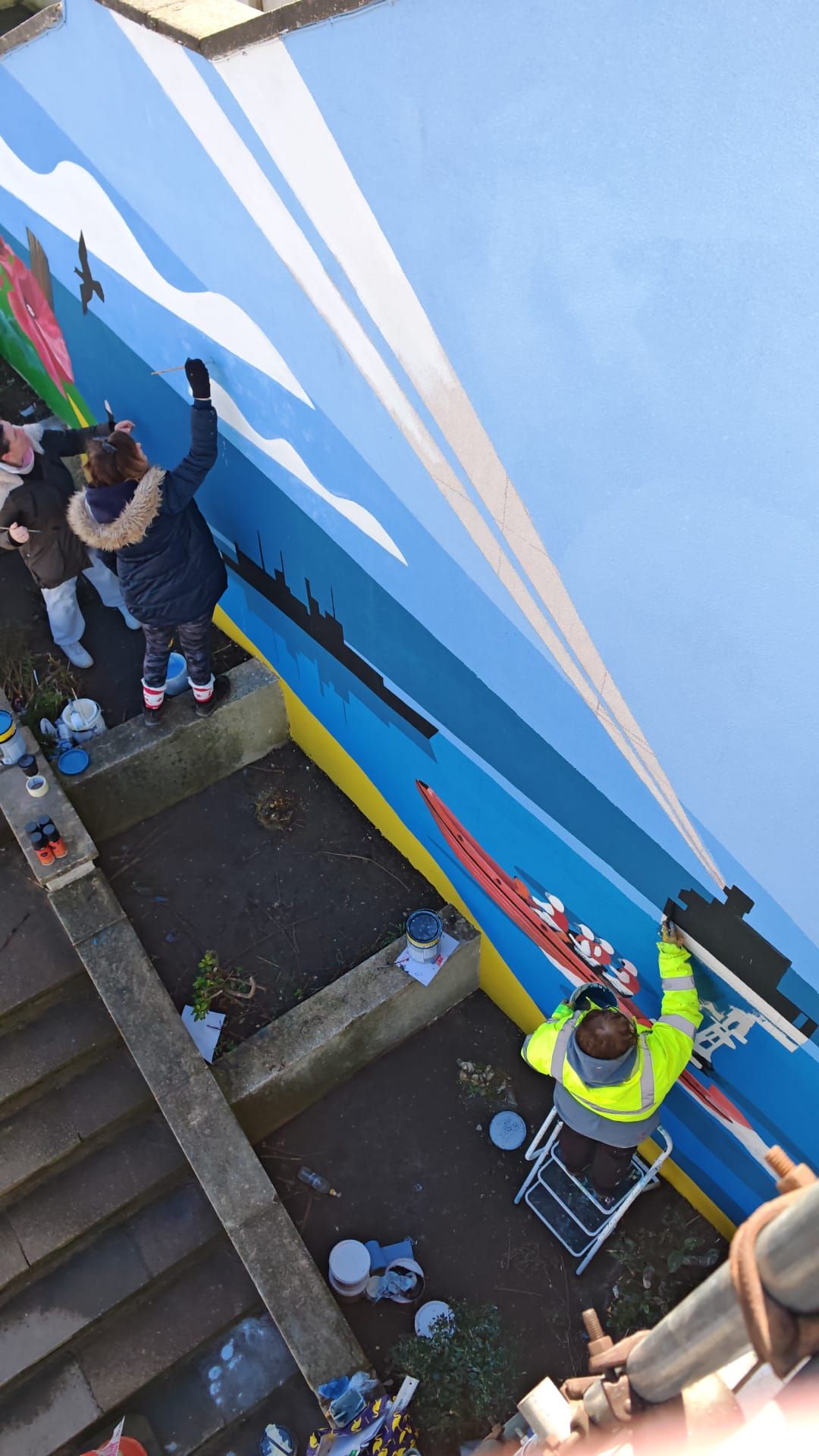 A group of people are painting a mural on a wall.
