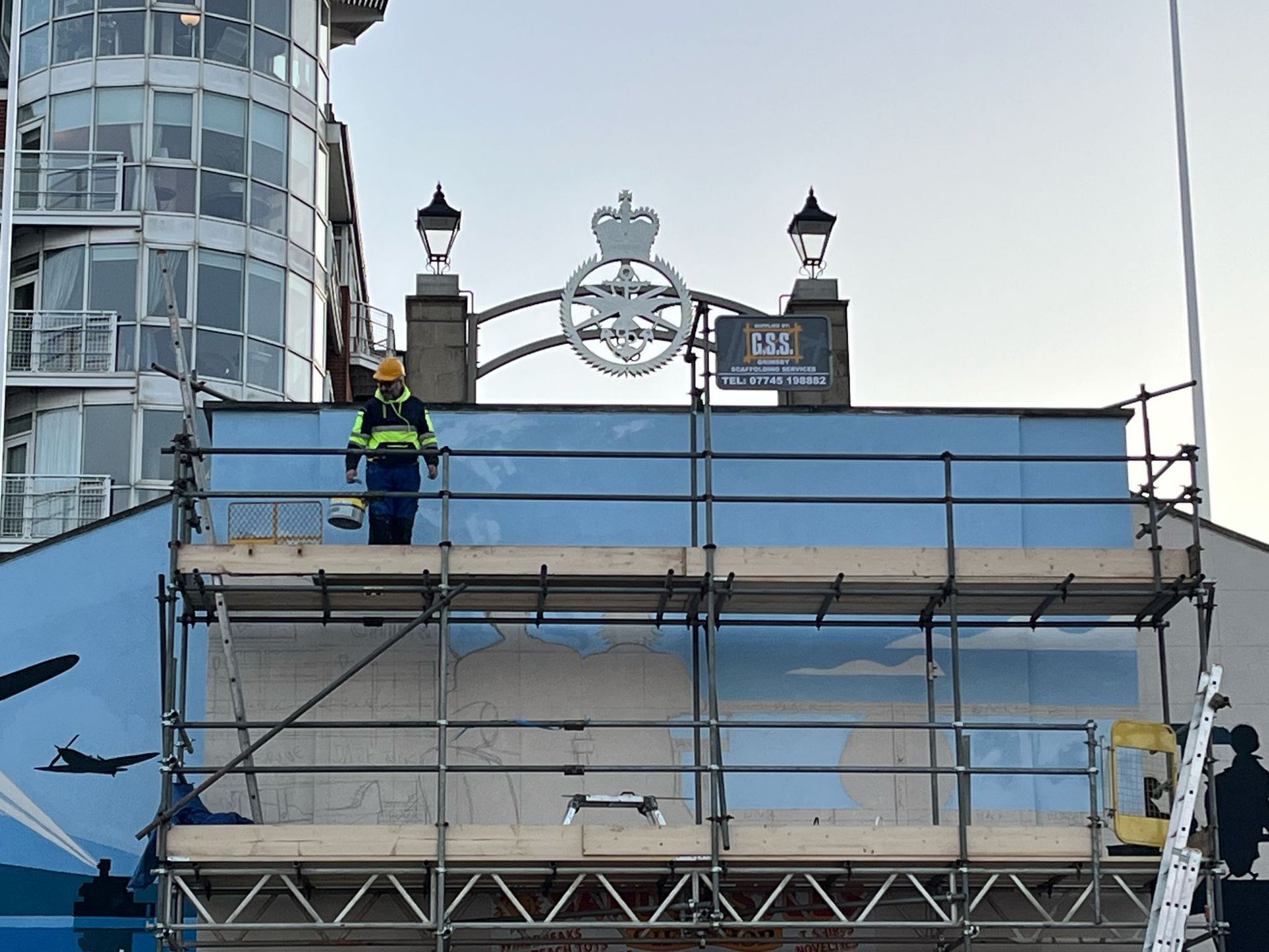 A man is standing on a scaffolding on top of a building.