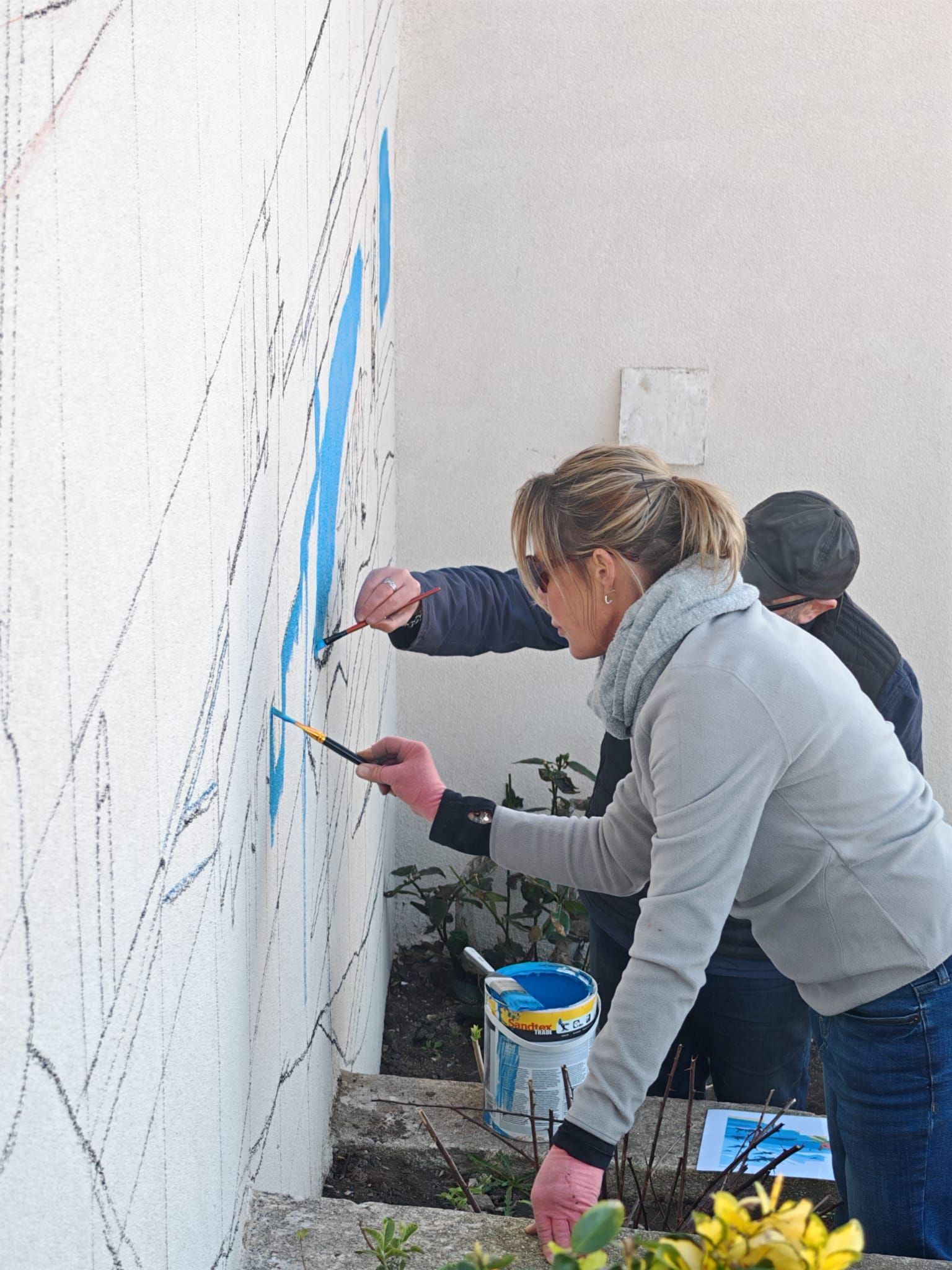 A woman is painting a wall with blue paint