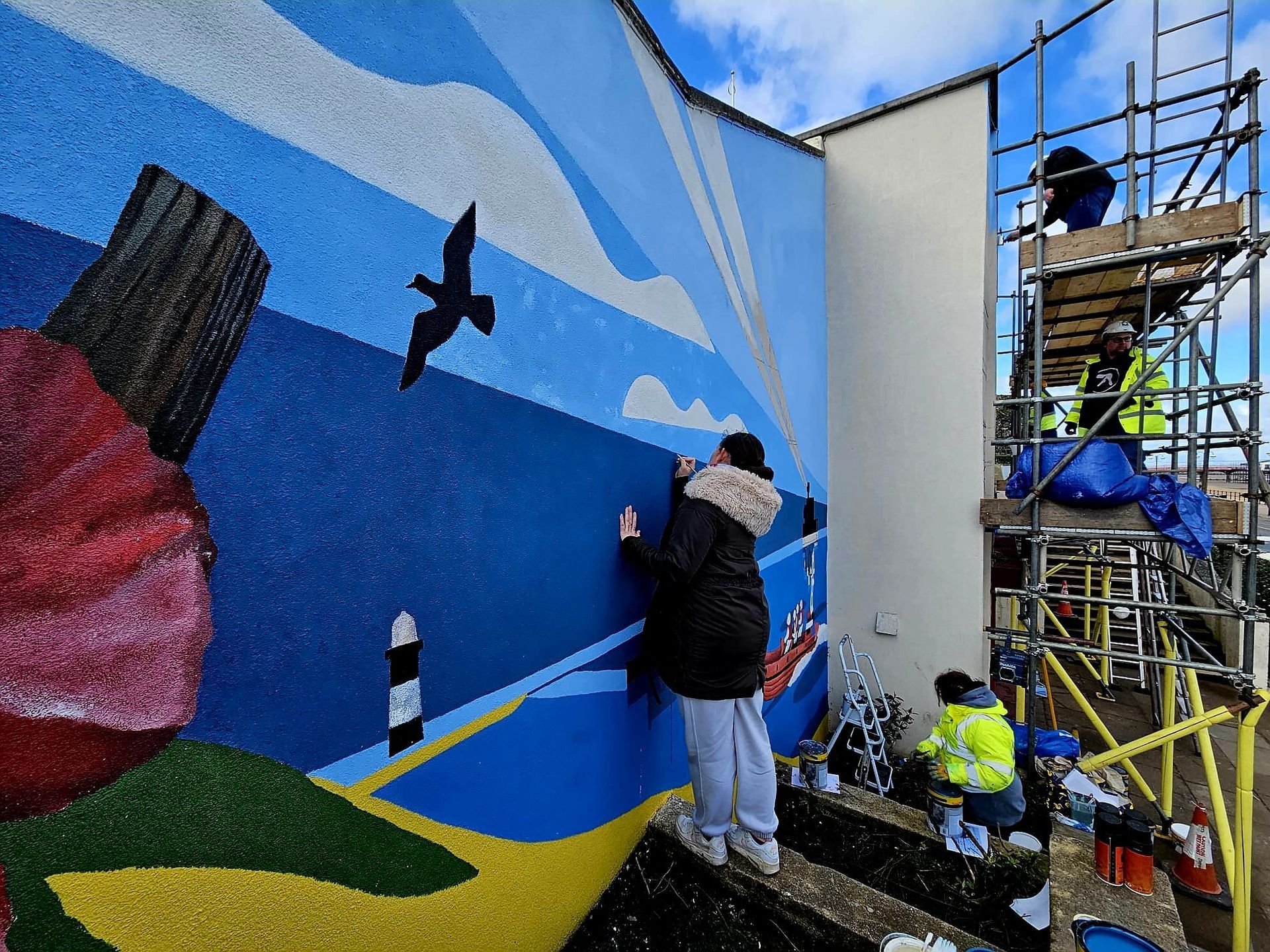 A group of people are painting a mural on the side of a building.