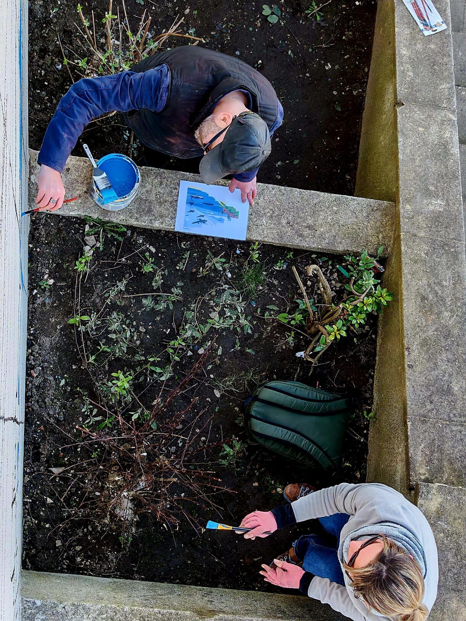 A man and a woman are working in a garden.