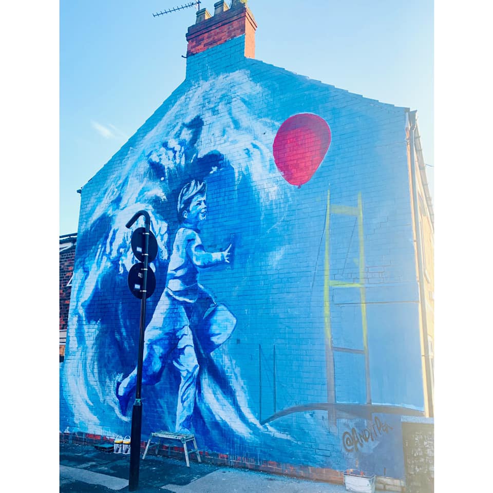 A large mural on the side of a building shows a boy holding a red balloon.