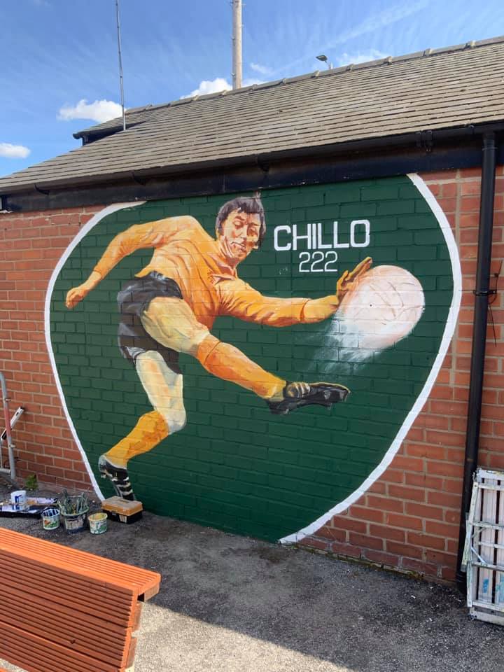 A mural of a man kicking a soccer ball on the side of a building.
