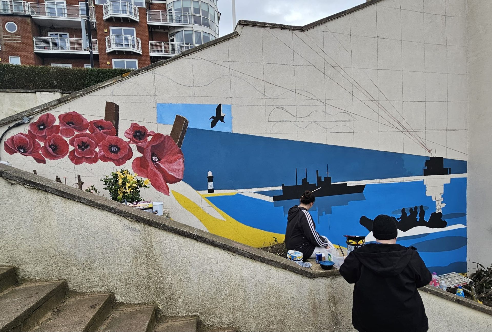 A man is painting a mural on the side of a building.