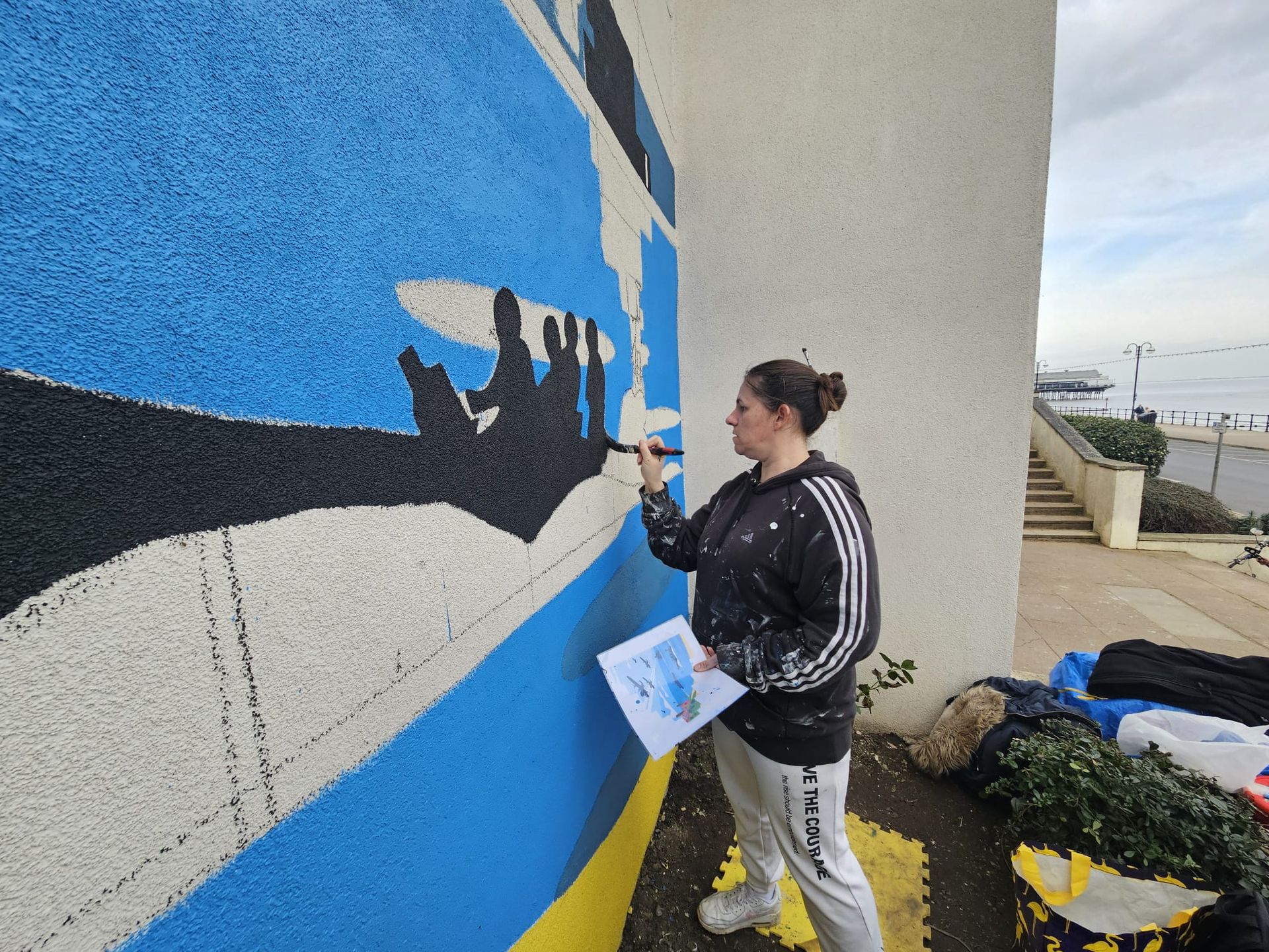 A woman is painting a mural on the side of a building