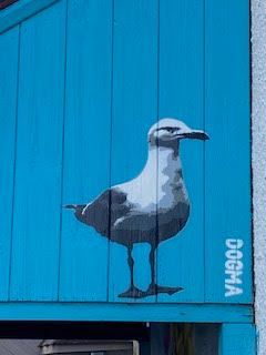 A seagull is painted on a blue wooden wall.