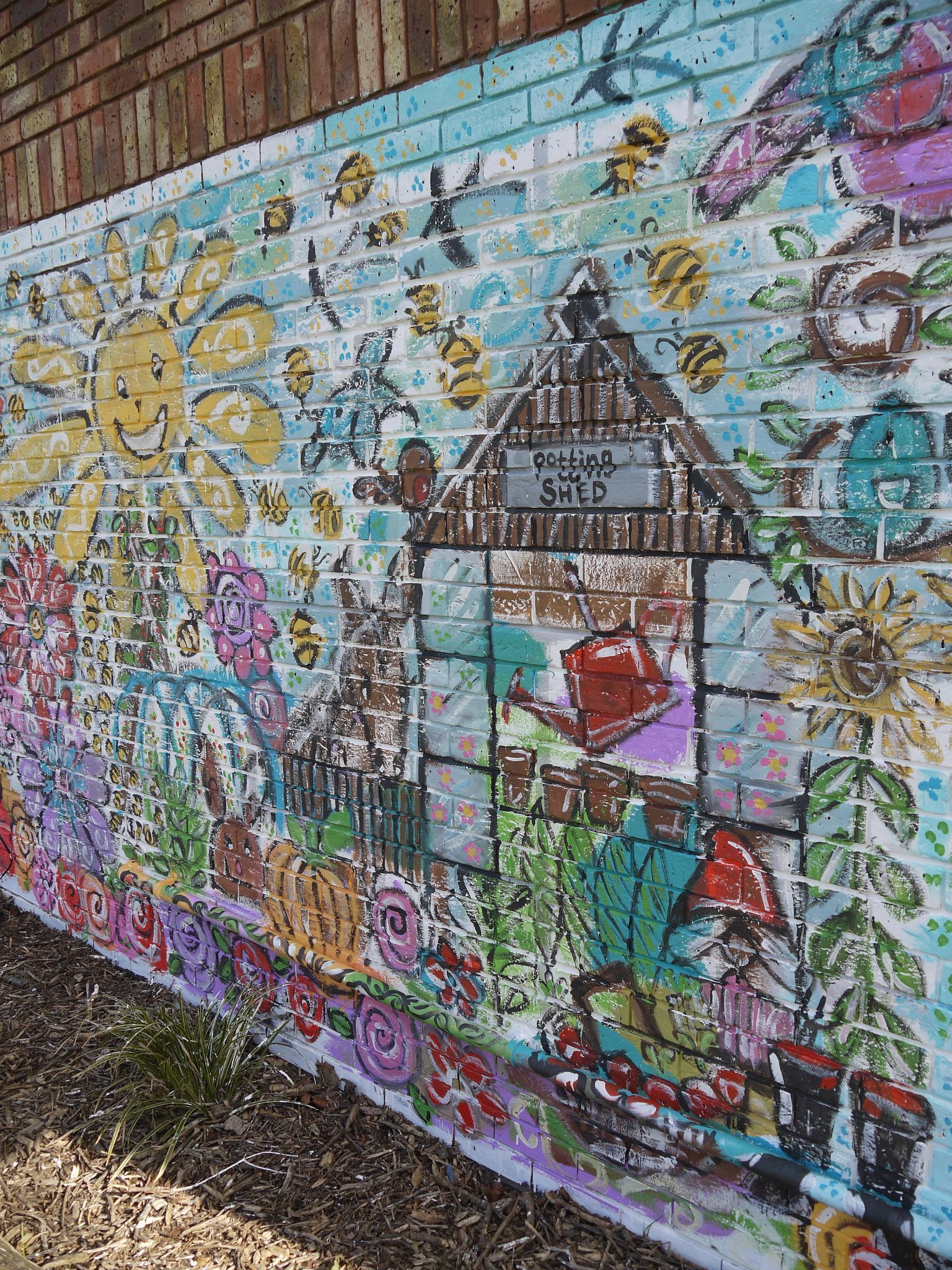 There is a large mural on the side of a brick wall.