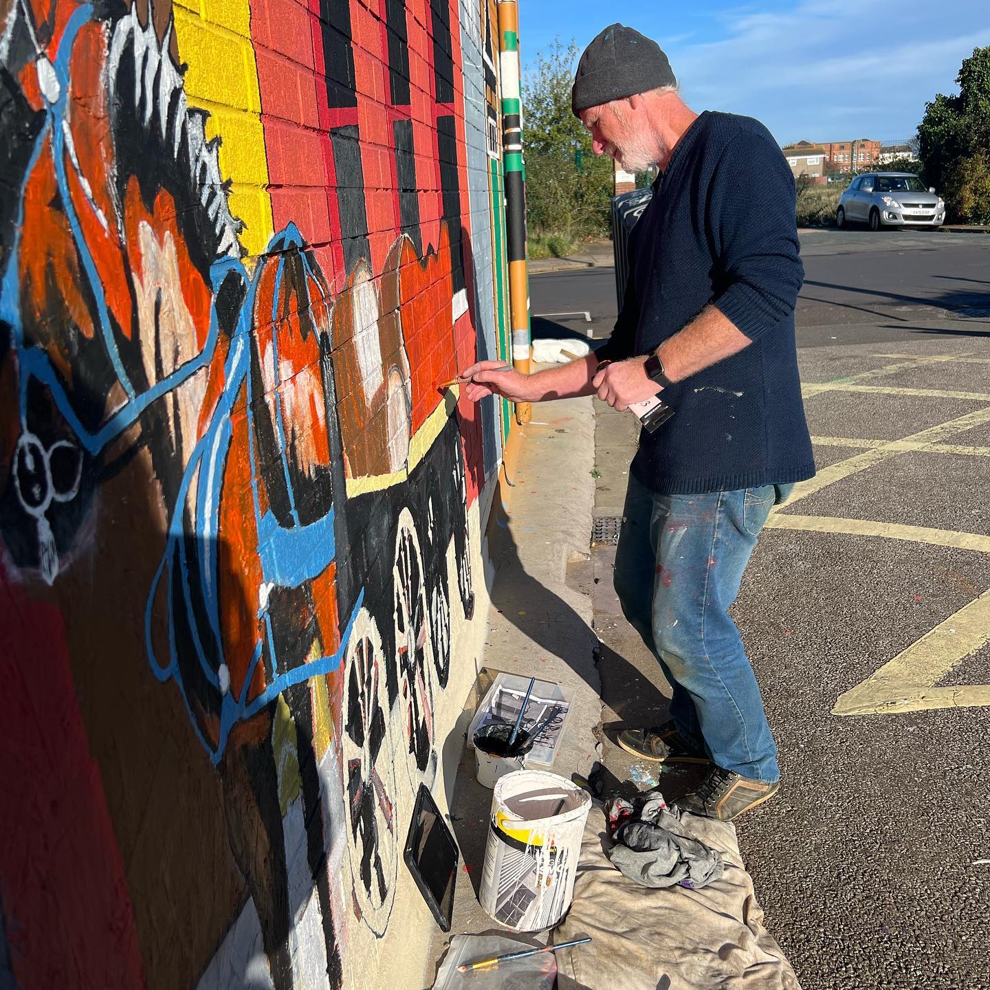A man is painting a mural on the side of a building