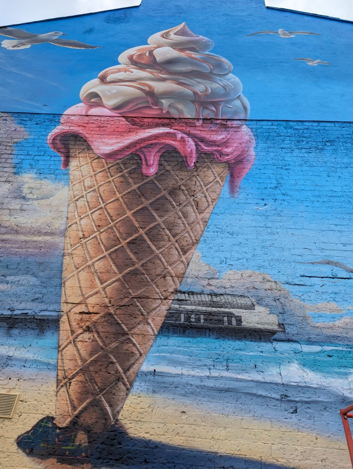 A giant ice cream cone is painted on the side of a building