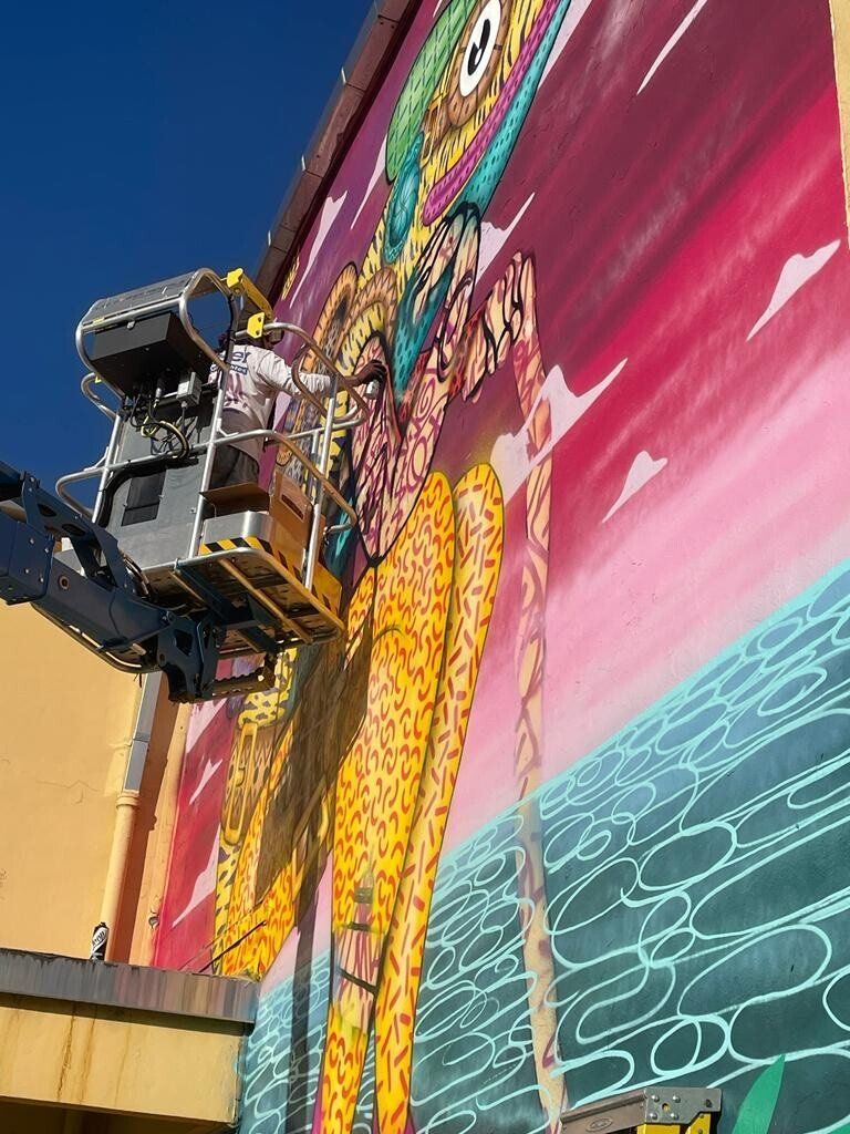 A man is painting a mural on the side of a building.