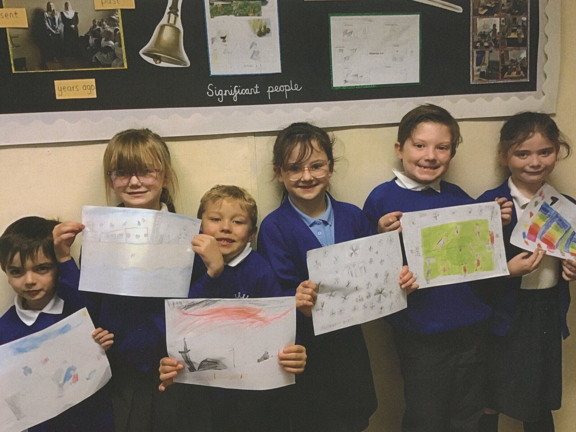 A group of children are holding up their drawings in front of a bulletin board that says symphony
