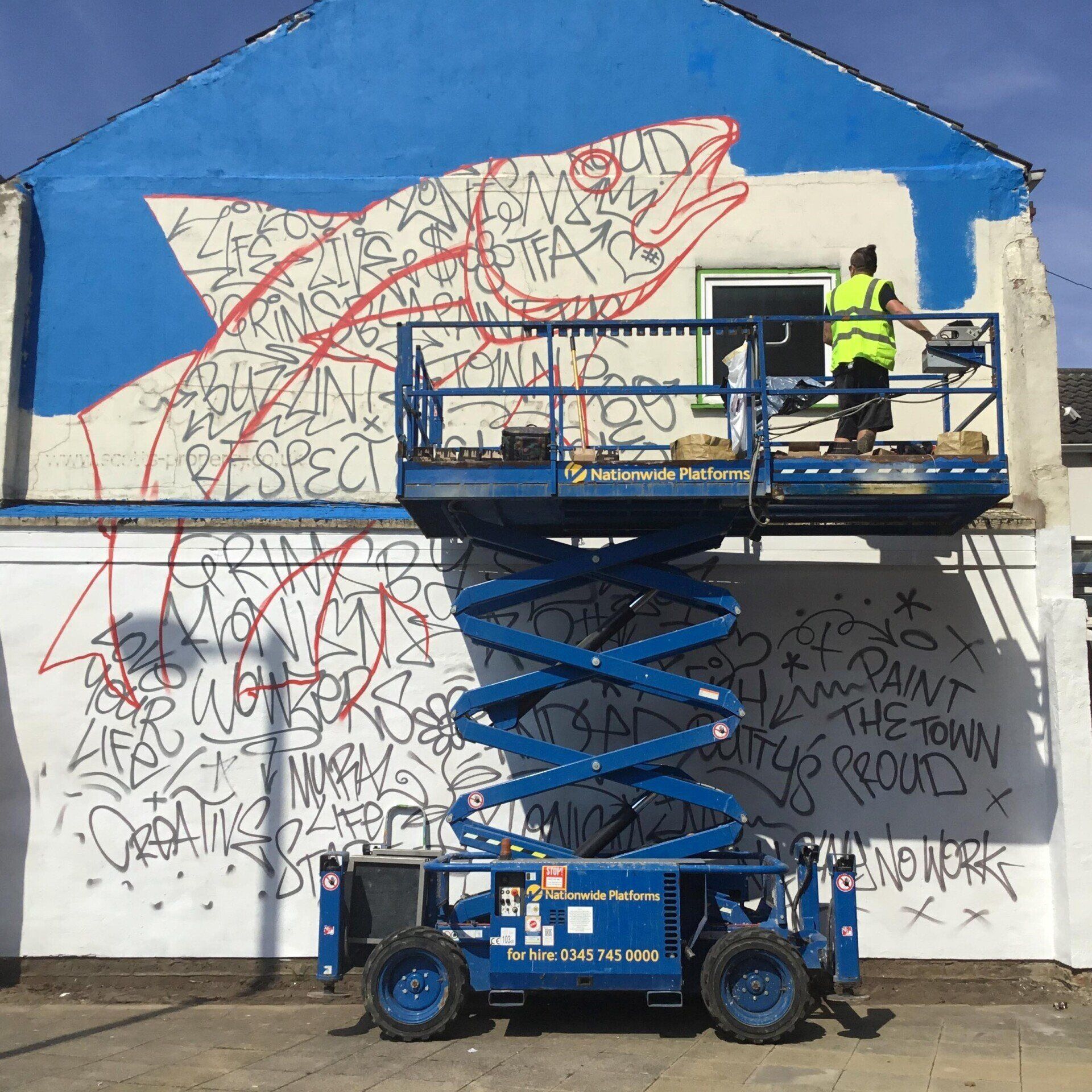 A man paints a mural on the side of a building