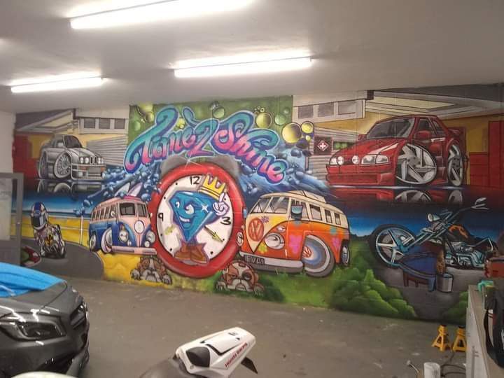 A motorcycle is parked in front of a mural that says home shine