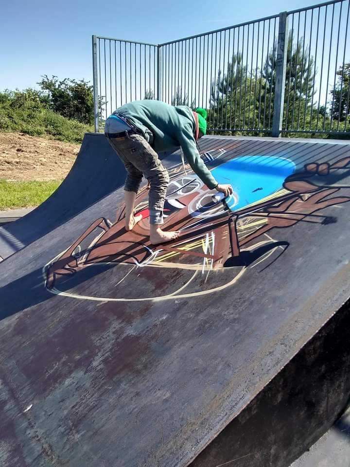 A person is painting a picture on a skateboard ramp.