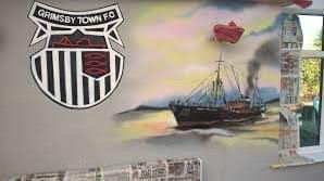 There is a painting of a ship on the wall.