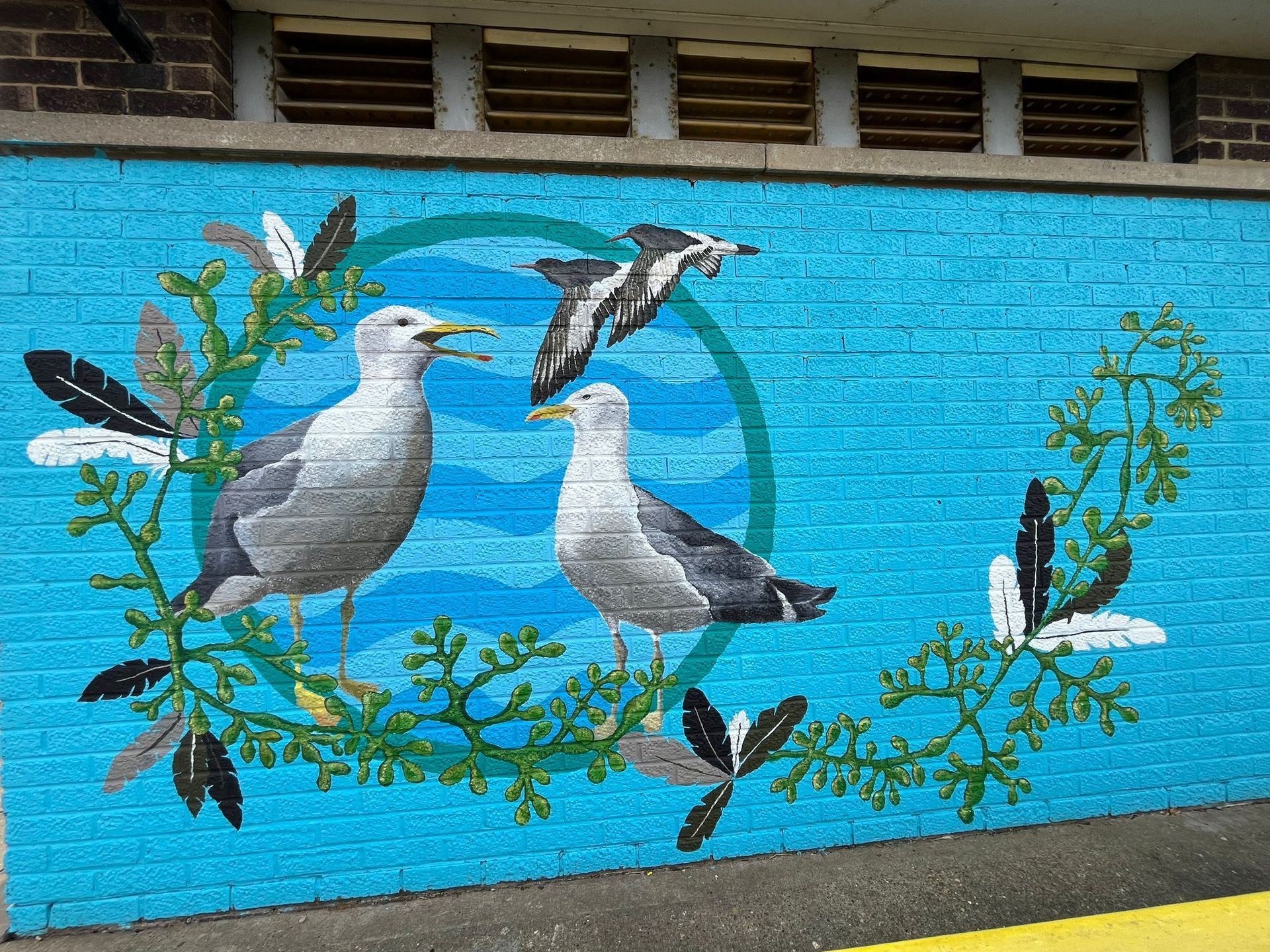 A painting of seagulls on a blue brick wall