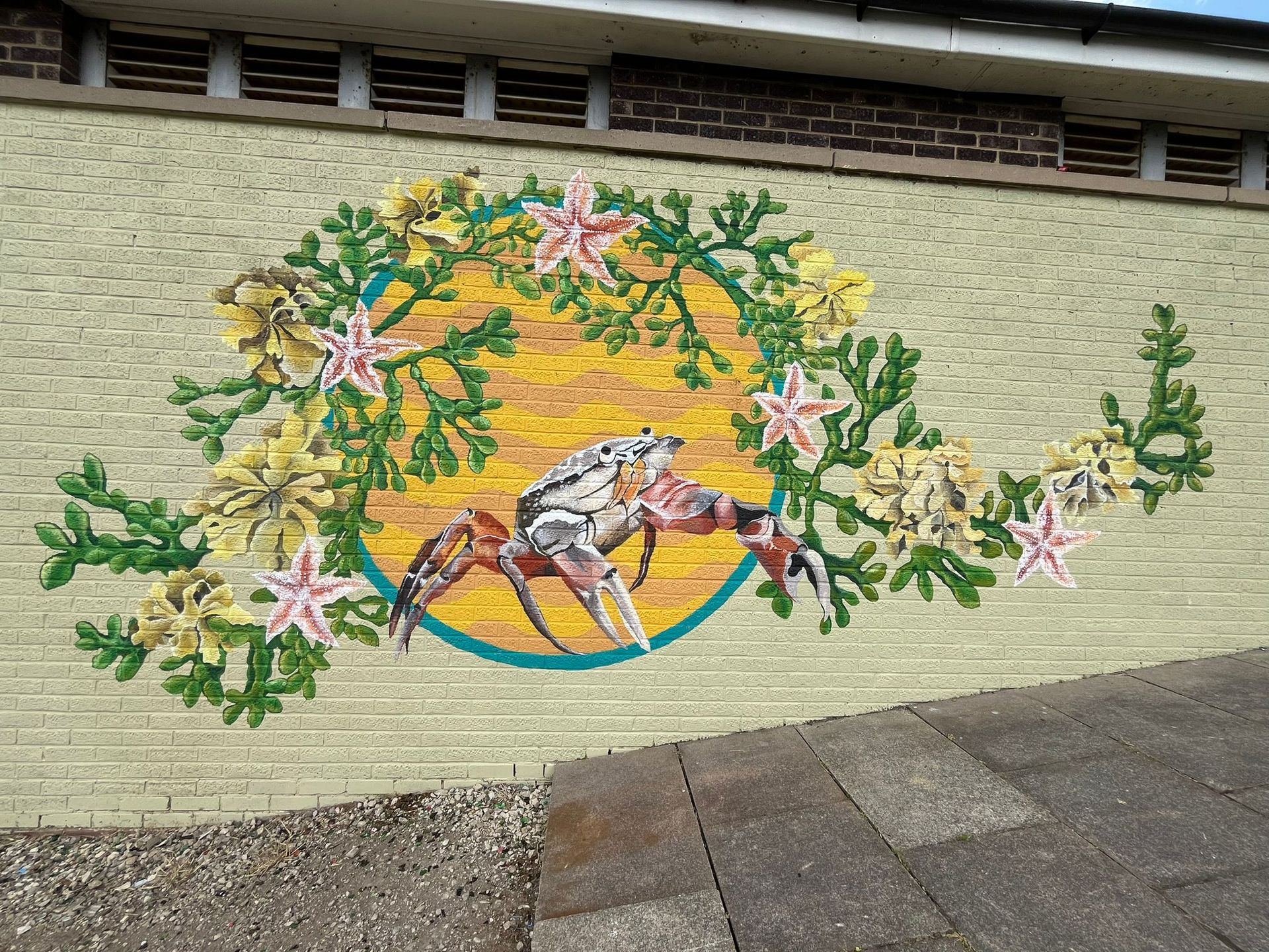 A crab is surrounded by flowers on a brick wall.