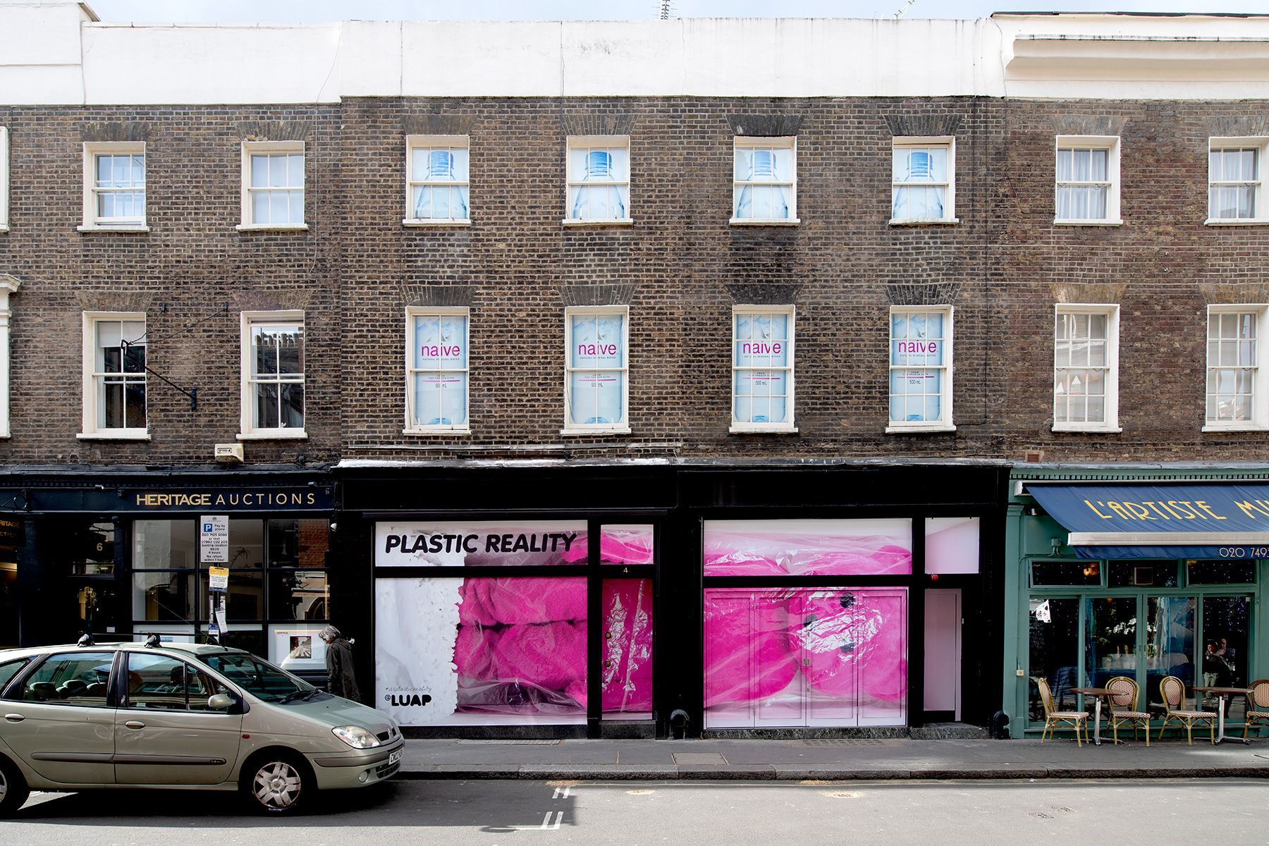 A car is parked in front of a building that says plastik beauty