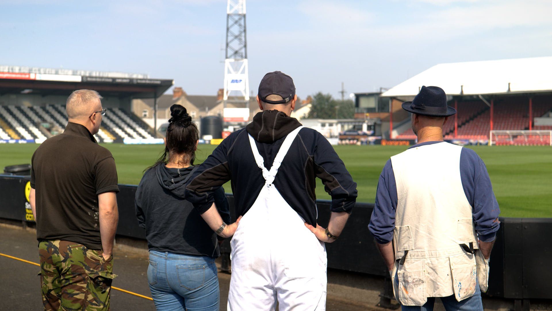 A group of people are standing in front of a soccer field.