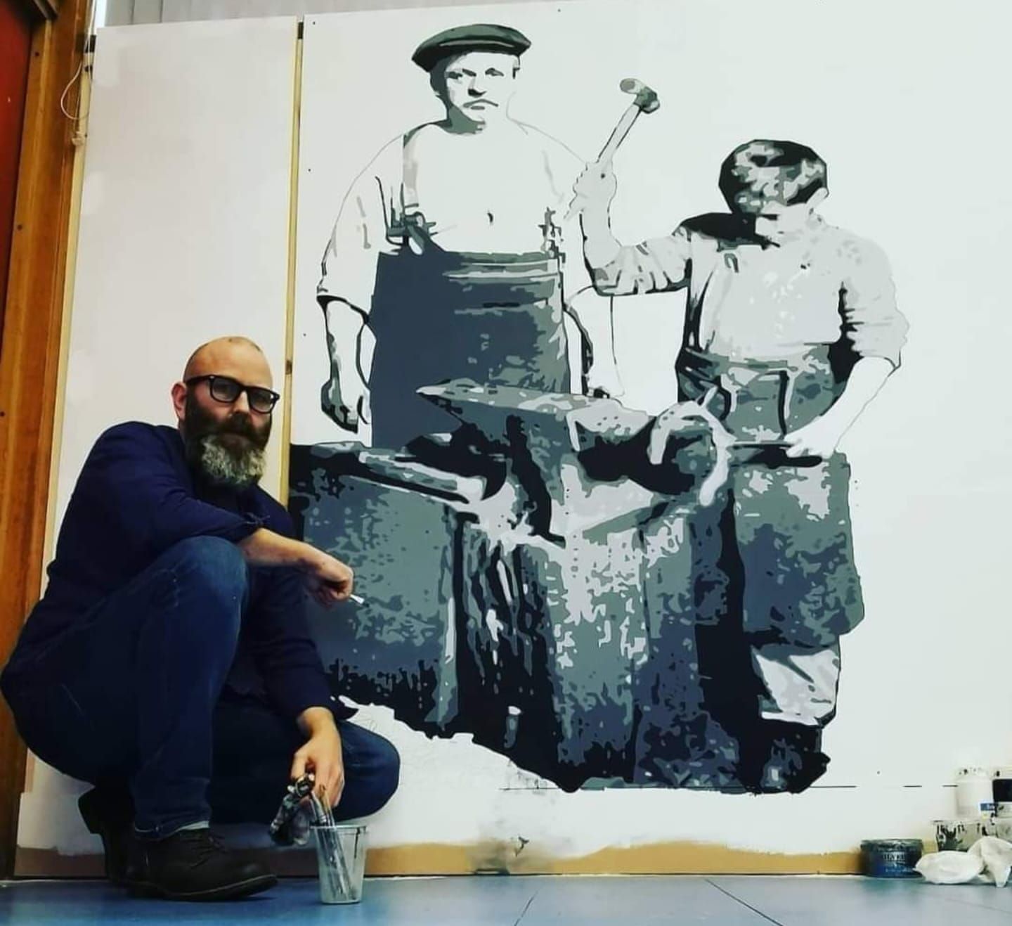 A man kneeling in front of a mural