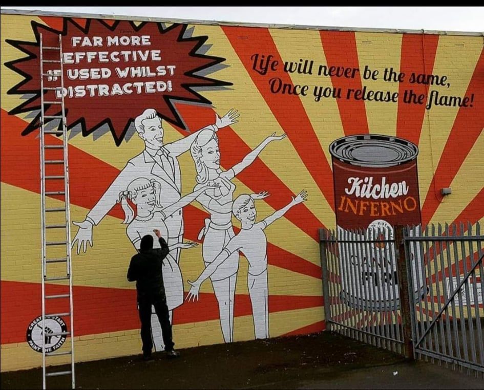 A man is painting a mural of a family and a can of kitchen inferno