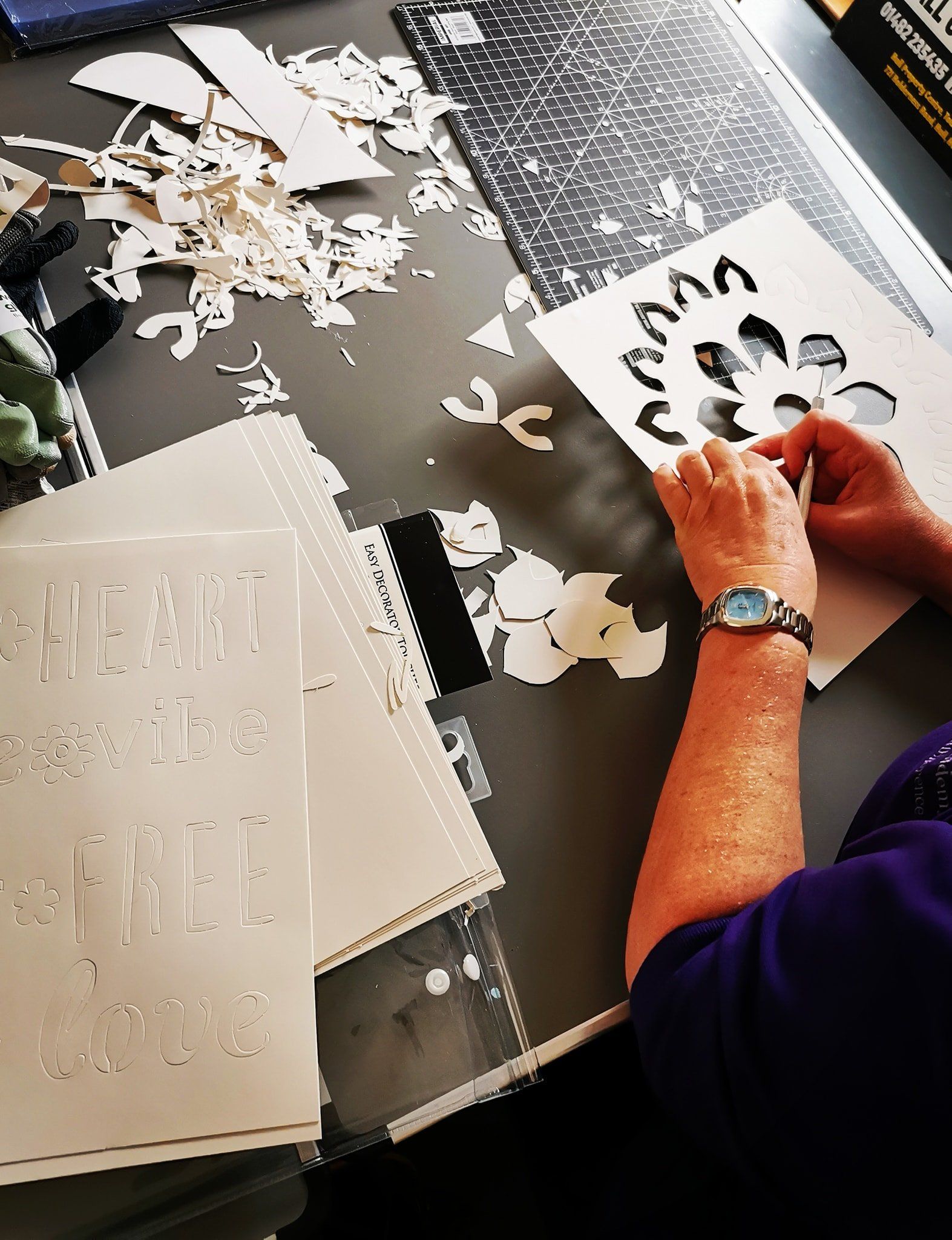 A woman is sitting at a table with a stencil on it