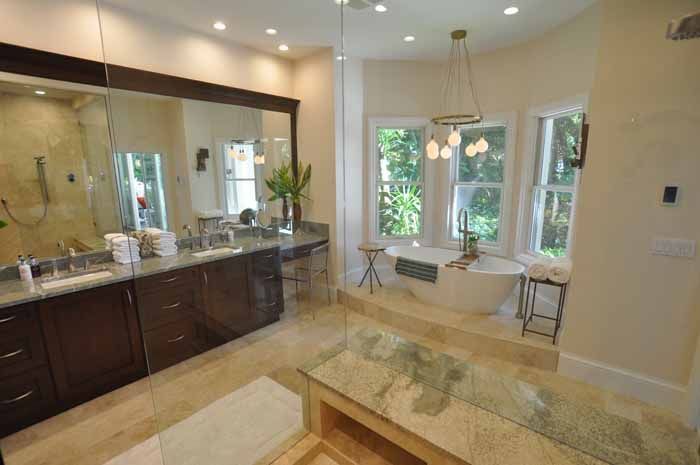 A bathroom with two sinks , a tub , and a large mirror.
