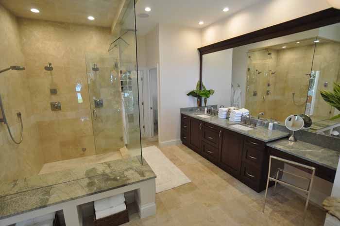 A bathroom with two sinks , a walk in shower and a large mirror.